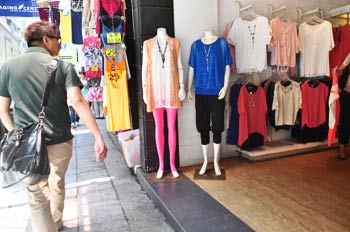Pedestrian passing clothing shop displays on Granville Road in Tsim Sha Tsui, Hong Kong